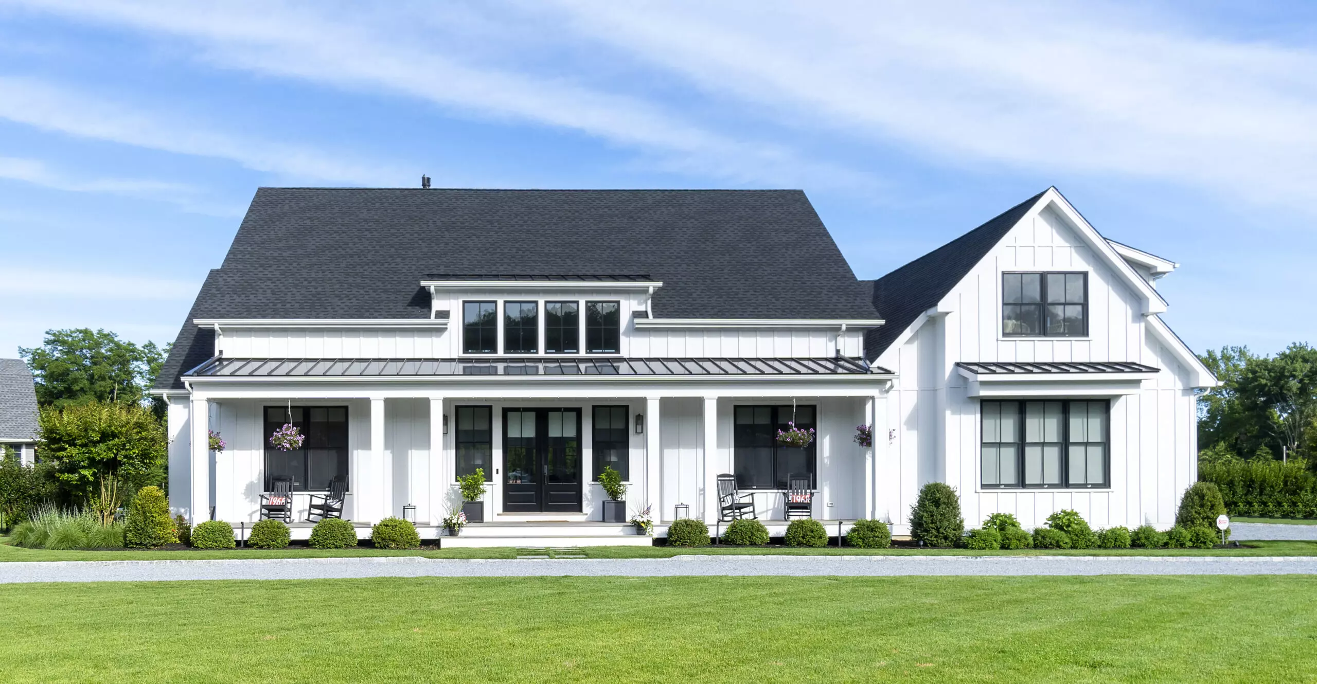 A large white house with black roof and windows.